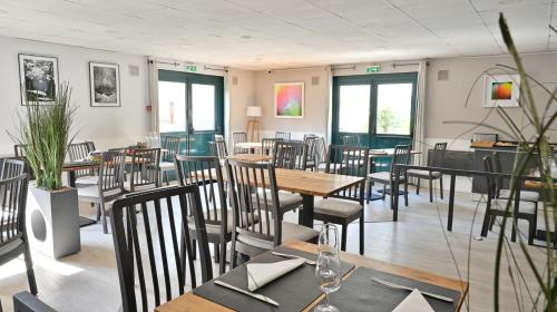 a dining room with tables and chairs and windows at Les Chevaliers des Balances in Saint-Aubin