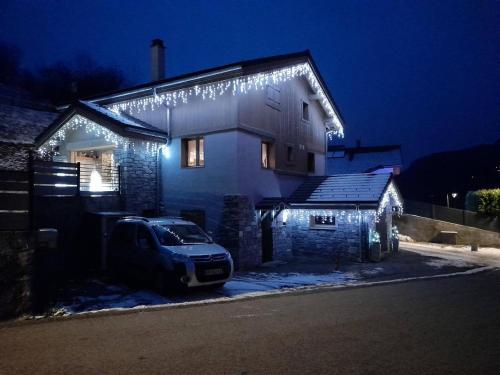 a car parked in front of a house with christmas lights at Joli Appartement Sur Le Bois in Aigueblanche