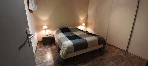- une chambre avec un lit noir et blanc et 2 lampes dans l'établissement Joli Appartement Sur Le Bois, à Aigueblanche
