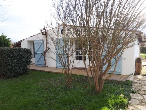 uma casa branca com uma porta azul e árvores em Loft atypique pour 2 personnes em Nieulle-sur-Seudre