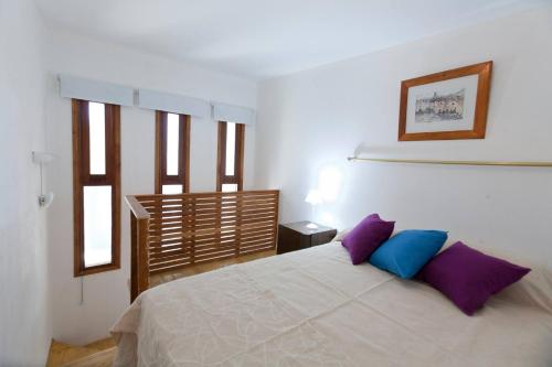 sypialnia z białym łóżkiem z fioletowymi i niebieskimi poduszkami w obiekcie Civitella Appart w mieście Villa Mercedes