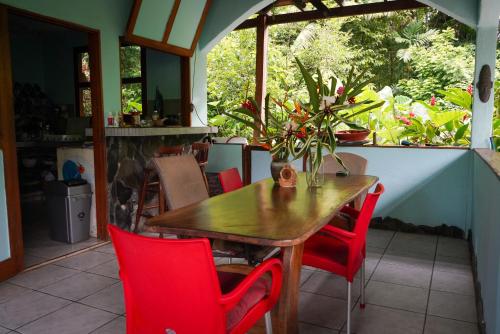 a wooden table and red chairs on a patio at Blue Butterfly House in Pavones