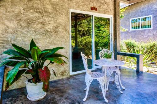 a patio with a table and chairs and a plant at New Moon in Thongsala