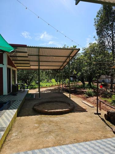 a patio with awning and a fire pit at Farmhouse with Pool - Kalavady Farmstay in Baindūru