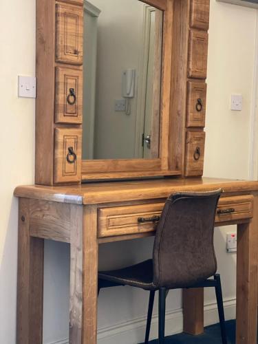 a wooden desk with a mirror and a chair at King's Cross Quiet Apartment in London