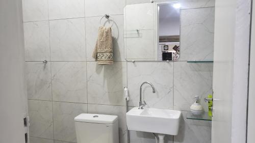 a white bathroom with a toilet and a sink at Pousada e Hostel sol e mar in João Pessoa