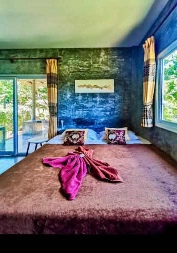 a bedroom with a large bed with purple blankets on it at New Moon in Thongsala