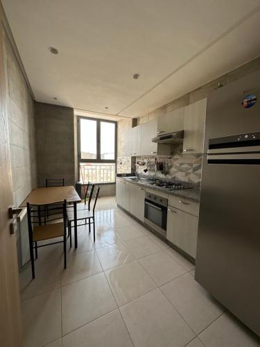 Luxueuse appartement في أغادير: مطبخ مع طاولة وموقد وطاولة وكراسي