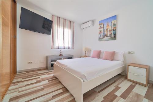 1 dormitorio con 1 cama blanca y TV de pantalla plana en Playa apartamento, en Málaga