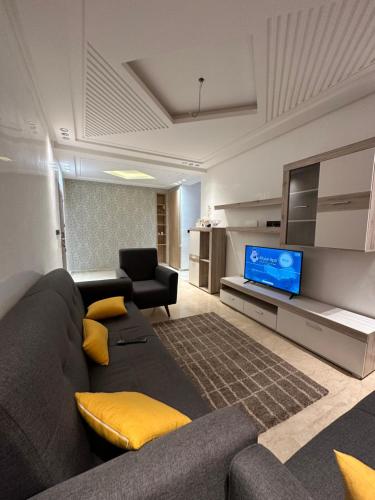 Luxueuse appartement في أغادير: غرفة معيشة مع أريكة وتلفزيون بشاشة مسطحة