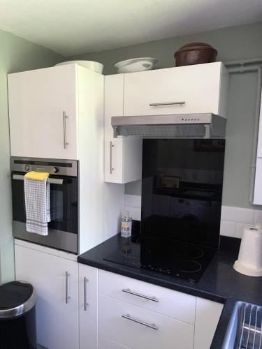 a kitchen with white cabinets and a black stove top oven at 1 Bedroom Apartment Central Basingstoke in Basingstoke