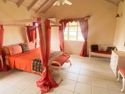 a bedroom with a canopy bed with red curtains at Terracotta Enterprise - Gated Community Home in Christ Church