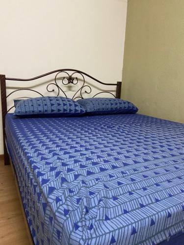 un letto con piumone e cuscini blu sopra di ADEELA HOMESTAY @ BANDAR KUANTAN a Kuantan