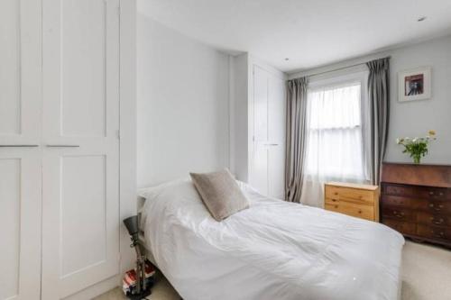 a bedroom with a bed and a dresser and a window at Flat cannot be booked in London