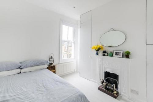 a white bedroom with a bed and a fireplace at Flat cannot be booked in London