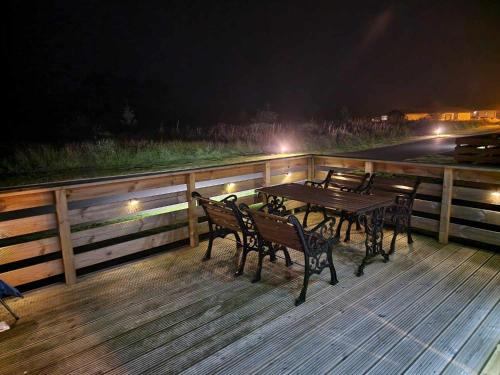 a table and chairs on a wooden deck at night at Loch's Heaven 67 in Balminnoch