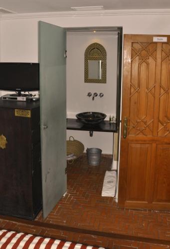 a bathroom with a sink and a door and a television at Hotel Blanco Riad in Tetouan