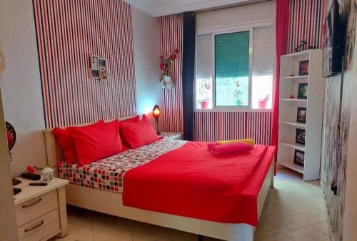 a bedroom with a bed with red sheets and a window at StayHere, Nice Apartment with Garden and sea view, 1 min walk From Beach, High-Speed WI-FI in El Jadida