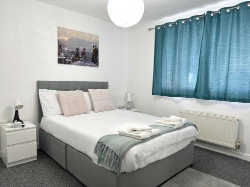 a bedroom with a large bed with blue curtains at Clover Apartments in Hadleigh