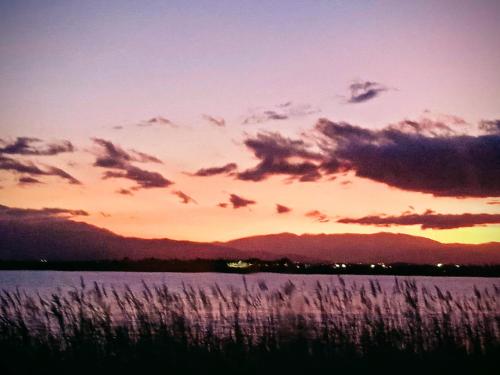 a sunset over a body of water with mountains at Camping siblu vue sur Canigou in Canet-en-Roussillon