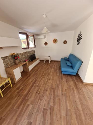 a living room with wooden floors and a blue chair at B&B SERENA in Pietrafitta