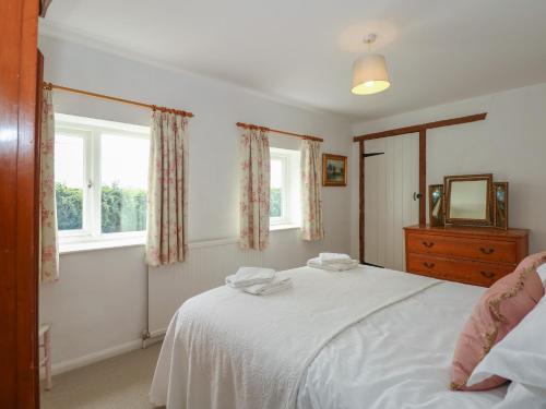 1 dormitorio con cama blanca y espejo en Horseshoe Cottage en Pentney