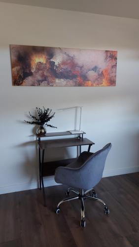 a desk and a chair in front of a desk and a painting at City Apartment, Ferienwohnung 3 ZKDB, Balkon, Dachgeschoss, nähe Düsseldorf in Krefeld
