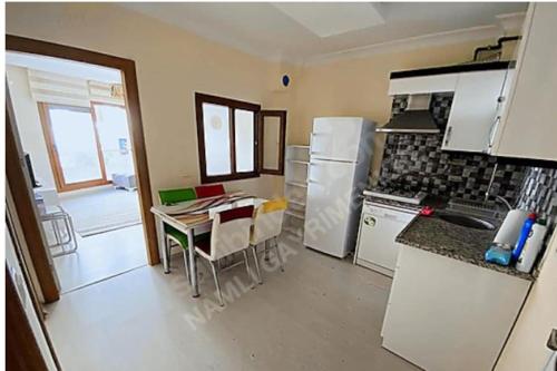 a kitchen with a table and a white refrigerator at Tınaztepe kampüse 5 dk 1+1 daire in Buca