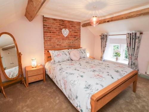a bedroom with a bed and a brick wall at Elsie's Escape in Matlock