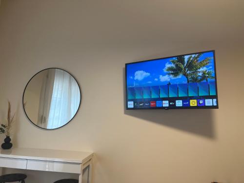 a flat screen tv on a wall with a mirror at KK Athens Fine Stay-Steps to Metro-Modern & Cozy Apartments in Athens