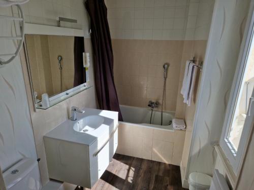 a bathroom with a sink and a bath tub at Hôtel De La Ferté in Chagny