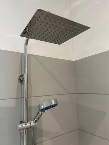 a shower with a shower head in a bathroom at H30 Apartman in Pécs