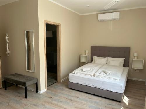 1 dormitorio con cama blanca y espejo en H30 Apartman, en Pécs