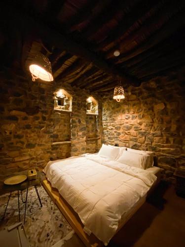 a bedroom with a large bed in a stone wall at Hanging Terraces المدرجات المعلقة in Al ‘Aqar