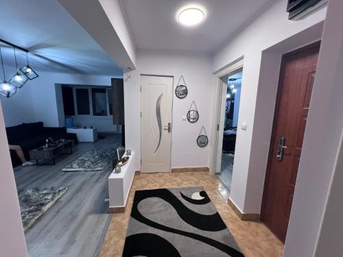 - un salon avec une porte blanche et un tapis noir dans l'établissement Apartament Maria, à Băile Govora