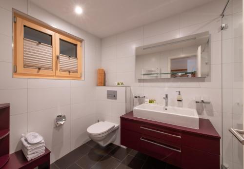 a white bathroom with a sink and a toilet at Chalet Bargsunna in Wengen