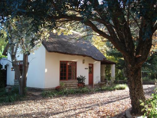 una piccola casa bianca con tetto di paglia di Peebles Cottage a Clarens