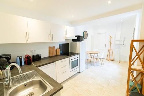 - une cuisine avec des placards blancs, un évier et une table dans l'établissement Gîte d'Artagnan 3 chambres, à Villers-Cotterêts