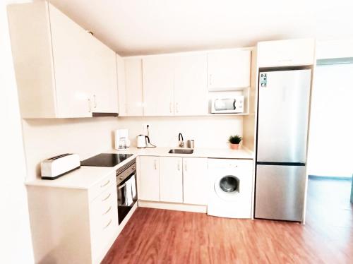 a kitchen with white cabinets and a stainless steel refrigerator at By Plaza Real Rooms in Barcelona