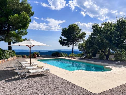 a swimming pool with two lounge chairs and an umbrella at Villa "Le Sortilège" vue panoramique et piscine in Tourtour