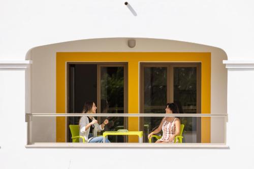 three women sitting in chairs on a balcony at Clube do Lago Hotel in Estoril