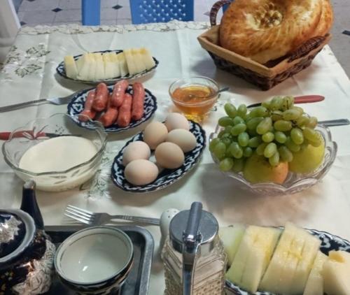 a table topped with plates of food with eggs and fruit at Olimxon Guest House in Bukhara