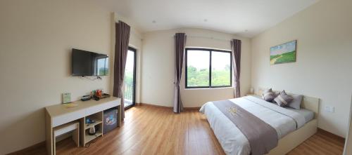 a bedroom with a bed and a desk and a television at Đồi Chè Hotel in Mộc Châu