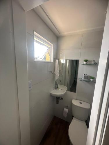 a white bathroom with a toilet and a sink at Village ITACIMIRIM SUMMER HOUSE in Camaçari