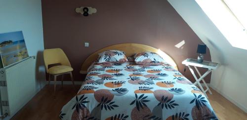 a bedroom with a bed with a comforter on it at Chambre d'hôtes de la voie bleue. in Plouguerneau