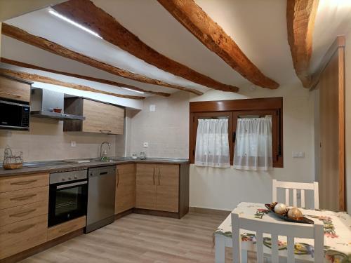 una cocina con armarios de madera, mesa y sillas en Casa Rural LA COSTANILLA en Lituénigo