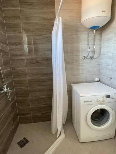 La salle de bains est pourvue d'un lave-linge et d'une douche. dans l'établissement Apartment in Mitrovicë, Kosovë, à Kosovska Mitrovica