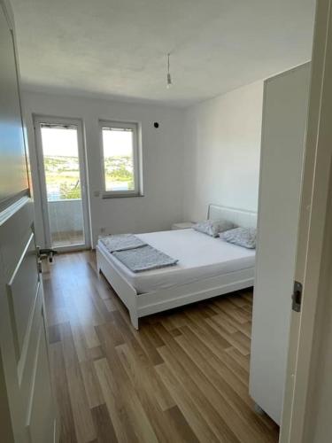 a white room with a bed and two windows at Apartment in Mitrovicë, Kosovë in Mitrovica