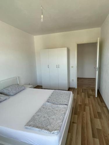 a bedroom with a large white bed and wooden floors at Apartment in Mitrovicë, Kosovë in Mitrovicë