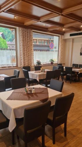 a dining room with tables and chairs and windows at Gasthof Hotel Kirchenwirt in Zell am Ziller